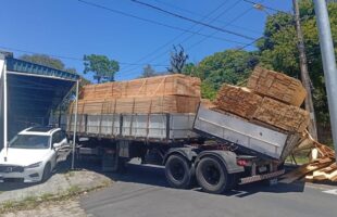 Carreta carregada com madeira tomba e atinge carro em Criciúma