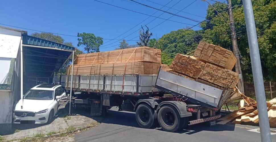 Carreta carregada com madeira tomba e atinge carro em Criciúma